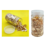 Open jar of golden gliding flakes spilling out on a bright yellow background