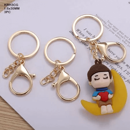 Set of 3 gold key rings with hooks, one featuring a boy sitting on a crescent moon